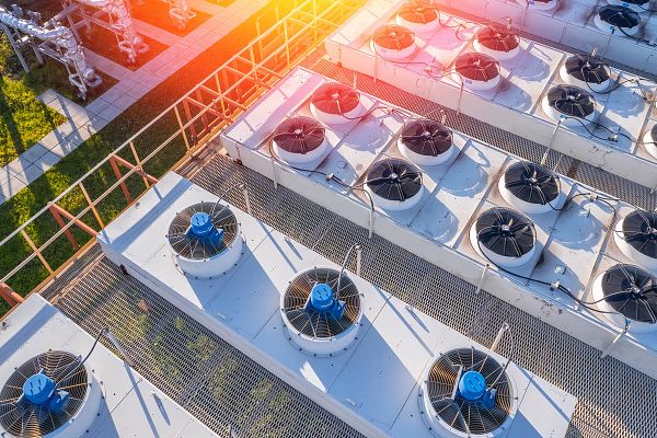 Industrial facility rooftop with multiple fan units providing cooling and energy optimization for HVAC systems.