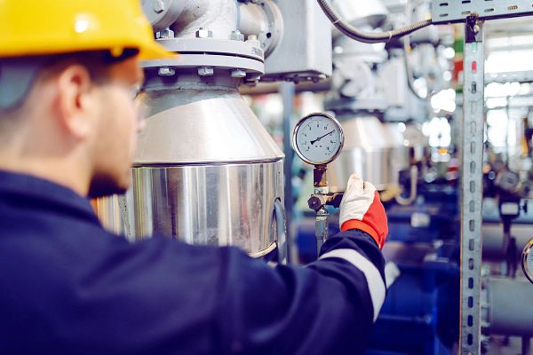 Technician monitoring a steam pressure gauge in a saturated steam HVAC system to prevent leaks and energy loss.